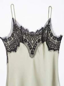 Detailed close-up of sage green satin dress with delicate black eyelash lace neckline