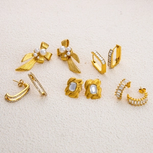 Detailed close-up of luxury 18K gold plated bow pearl earrings and zircon studs set