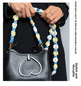 Close-up of black leather bag featuring a heart-shaped zipper and colorful floral woven strap