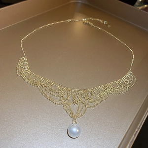 Macro detail of 24K gold plated lace mesh necklace with a white pearl pendant