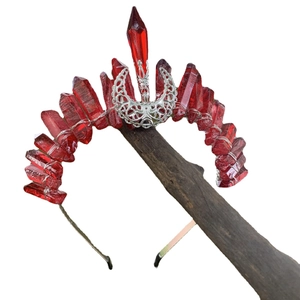 Handmade red crystal crown headband with silver moon detail on a wooden display
