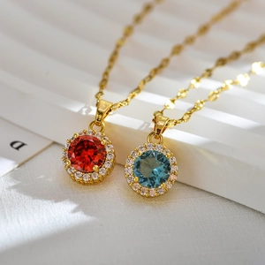 Elegant gold necklaces with halo-set red and teal crystal pendants on white display