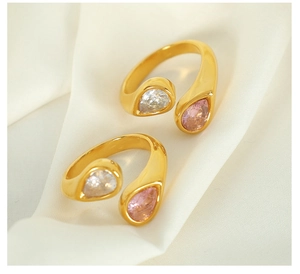 Close-up of gold open rings with pear-cut pink and clear zircon stones on white silk