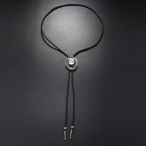 Detail of vintage silver cowboy hat pendant on black braided leather bolo tie necklace