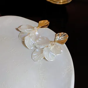 Macro shot of 3D floral petal earrings with golden shell studs and zircon accents