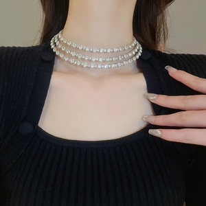 Macro detail of silver-tone triple layer choker necklace with shimmering round rhinestones