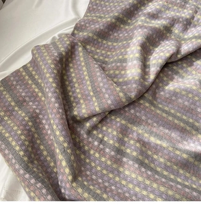 Detailed macro view of rainbow plaid thick knit scarf with violet and yellow weave texture