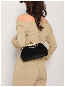 Elegant black velvet clutch bag with golden metal handle worn by model in back view