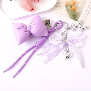 Detail of purple bow keychain with woven rope, pearls, silver heart and balloon dog charm
