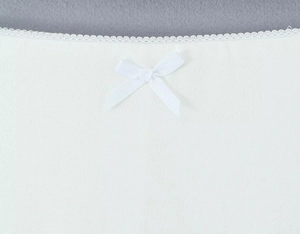Dettaglio di tessuto a maglia bianco con bordo in pizzo e piccolo fiocco decorativo