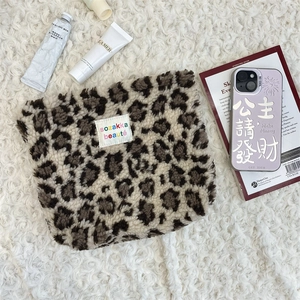 Close-up of leopard print plush makeup bag with soft texture and brand label