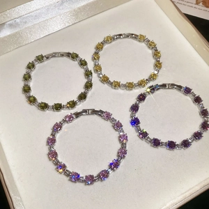 Detailed shot of tennis bracelets with pink, green, yellow, and purple zircons in a box