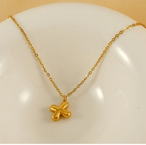 Detailed view of a gold 3D bubble letter X pendant necklace on elegant ceramic