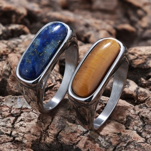 Close-up of vintage steel rings with natural lapis and tiger eye stones on wood