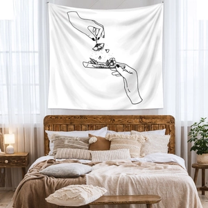Close-up of black line art tapestry with floral hands above a cozy bed and plants