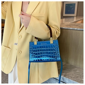Detail of electric blue croc-effect handbag with tortoiseshell handle and gold hardware