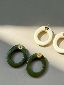 Close-up of resin geometric oval earrings in green and off-white with metal studs