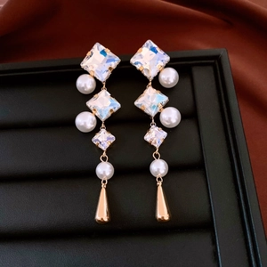 Detail of drop earrings with square colorful crystals and white pearls on gold metal