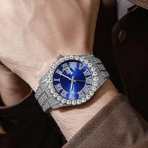 Close-up of luxury hip hop watch featuring blue dial, Roman numerals, and paved rhinestones