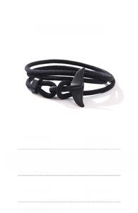 Detailed view of a 60cm black braided rope bracelet with whale tail charm for men