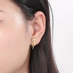 Close-up of elegant gold leaf-shaped titanium steel stud earrings on woman ear