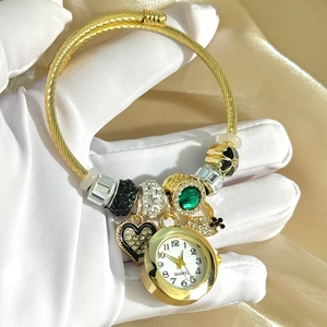 Detail of golden quartz watch bracelet with green crystal beads and floral pendants