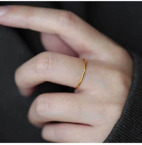 Detail view of slim gold titanium ring with tiny zircon gemstone worn on finger
