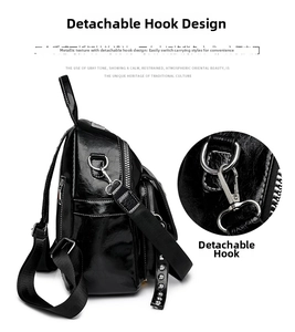 Close-up of black glossy backpack featuring silver rivets and detachable metal hook details