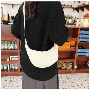 White corduroy crescent dumpling bag shown worn on a model in a cozy cafe setting