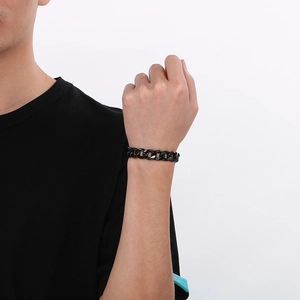 Gros plan d'un bracelet gourmette Figaro en acier inoxydable noir au poignet d'un homme