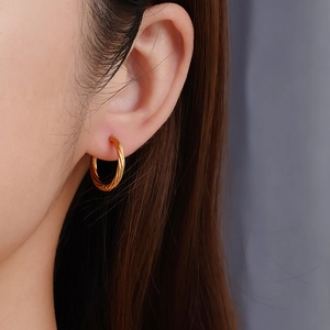 Créoles torsadées dorées en acier inoxydable plaqué 18K portées par un mannequin chic