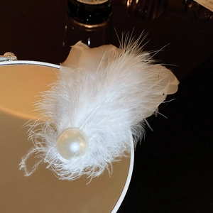 Detail of elegant white feather hair clip with a large pearl on a round mirror edge