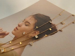 Detailed view of gold titanium necklaces with geometric zircon drops on magazine background