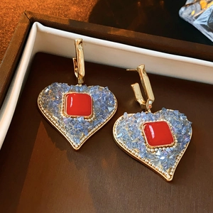 Detail of red square crystal heart earrings in vintage gold setting inside a jewelry box