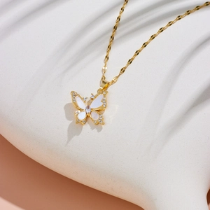 Macro detail of gold-plated butterfly necklace with white shell inlay and sparkling crystals