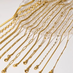 Various 18k gold plated stainless steel chains including snake and cuban styles on glass