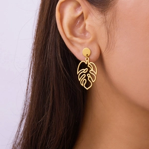 Detail of model wearing gold monstera leaf earrings with hollow cutout design