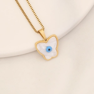 Macro detail of gold butterfly necklace with white shell inlay and blue evil eye accent