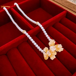 Macro detail of a freshwater pearl necklace with yellow crystal pendant in a red box