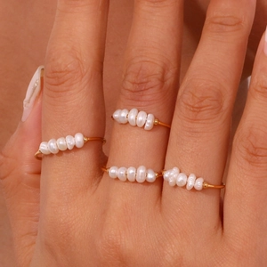 Detail of four delicate gold plated stainless steel rings with tiny white freshwater pearls