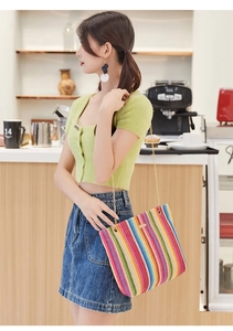 Rainbow woven shoulder bag with gold chain strap shown in a casual lifestyle cafe setting