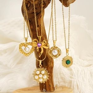 Gold plated necklaces with pearl and turquoise pendants on a natural wood branch display