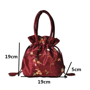 Detail view of burgundy satin bucket bag with floral embroidery and 19x19x5cm dimensions