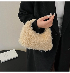 Détail du sac hobo beige en peau de mouton avec poignée en cuir et manteau noir chic