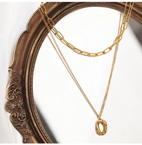 Detail of double-layer gold paperclip chain necklace with textured oval pendant