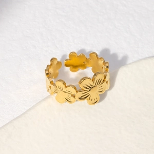 Detailed view of an open golden flower ring on a clean textured white surface