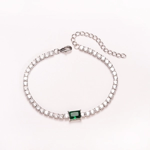 Detailed view of a silver tennis bracelet featuring a central emerald green rectangular stone