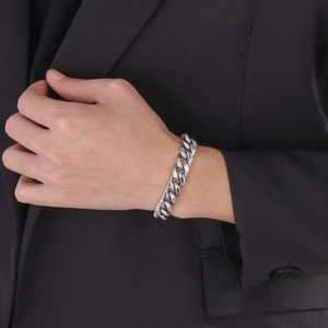 Bracelet gourmette argenté pour homme porté au poignet avec un costume noir