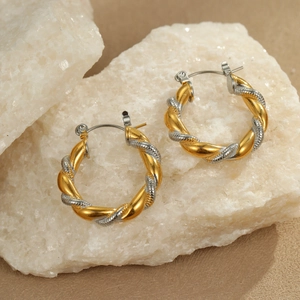 Two-tone twisted rope hoop earrings in gold and silver finish on natural stone background
