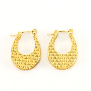 Gros plan de boucles d'oreilles dorées en forme de U avec texture taillée en diamant